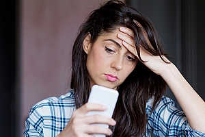 brunette woman with hand on forehead look at phone 