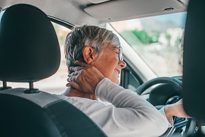 older womrn in a vehicle holding neck with pain