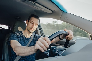 young man falling asleep behind the wheel intoxicated