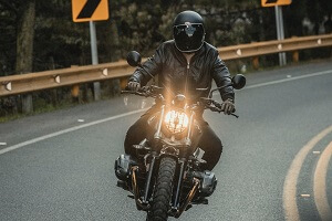 unrecognizable man riding motorcycle along road